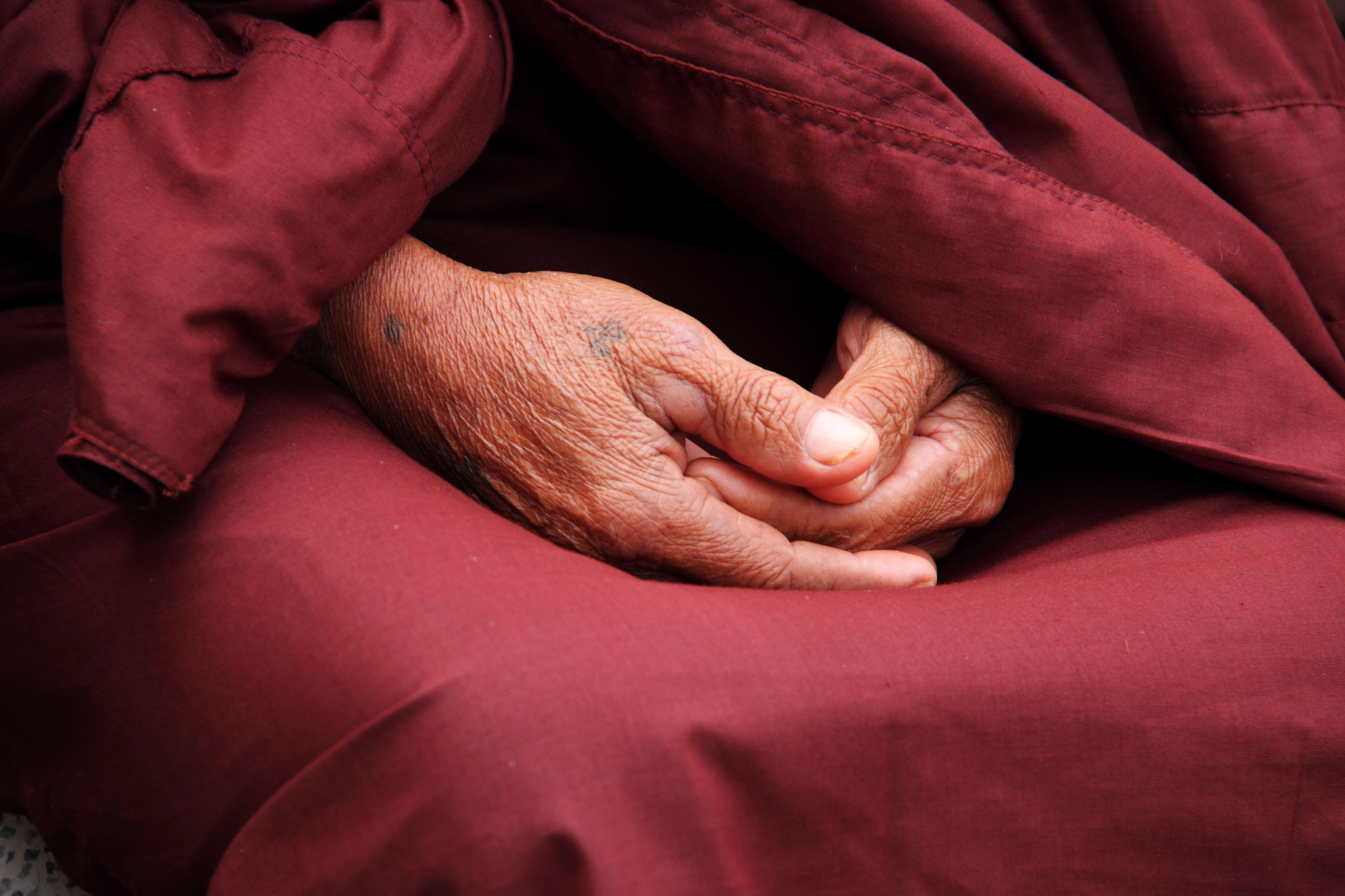 Hands folded together setting on red robe.